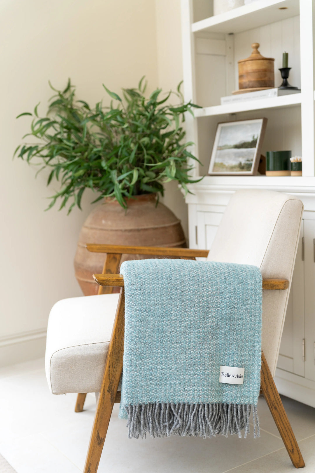 Belle & Aube Bamford Wool blanket in Seafoam, folded over the arm of an accent chair in a calm, lifestyle setting